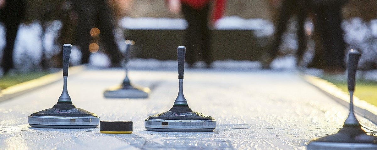 Eisstockbahn auf Schloss Wackerbarth Mehrere Eisstöcke stehen auf einer Eisbahn, unscharfe Personen im Hintergrund bei einer Winterveranstaltung.
